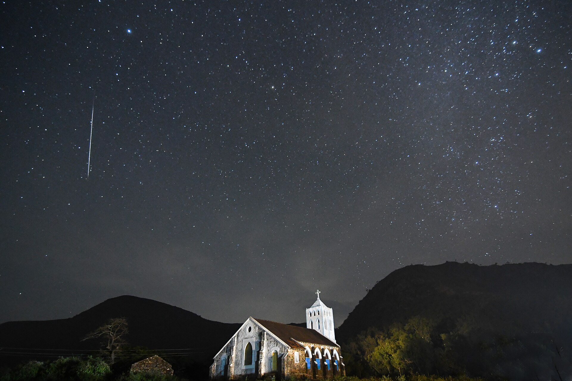 Étoile filante des Géminides au-dessus d'une vieille église, sous un ciel étoilé